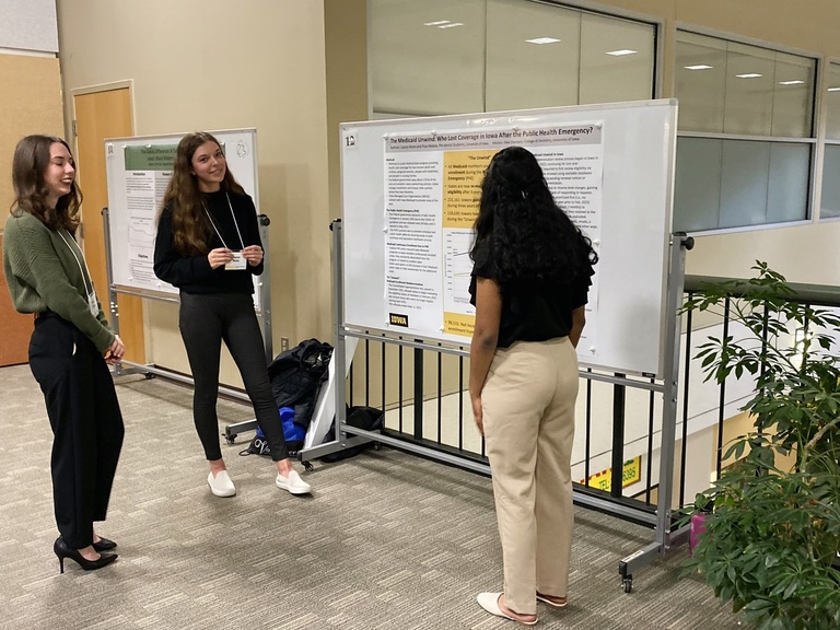Three students discuss a poster