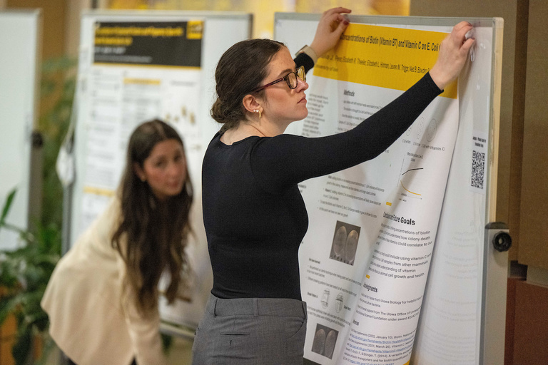 A student hangs her research poster