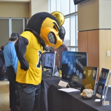 Herky overlooking a table at the research services fair