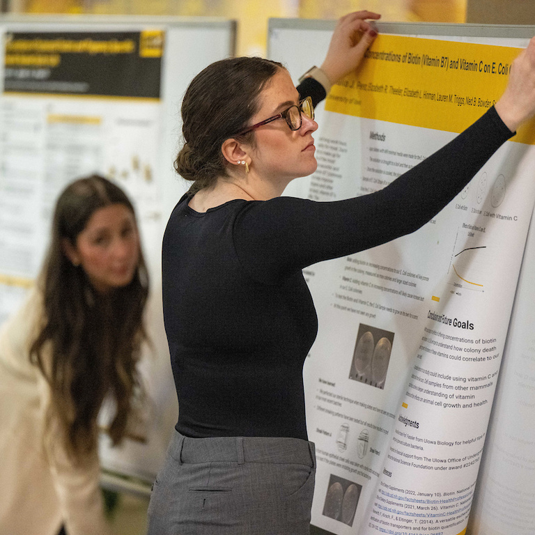 A student hangs her research poster