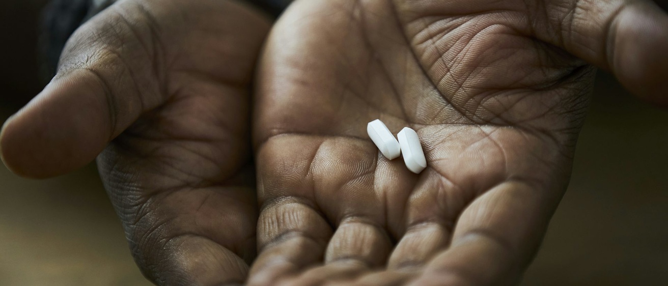 White pills cupped in the palms of a black man