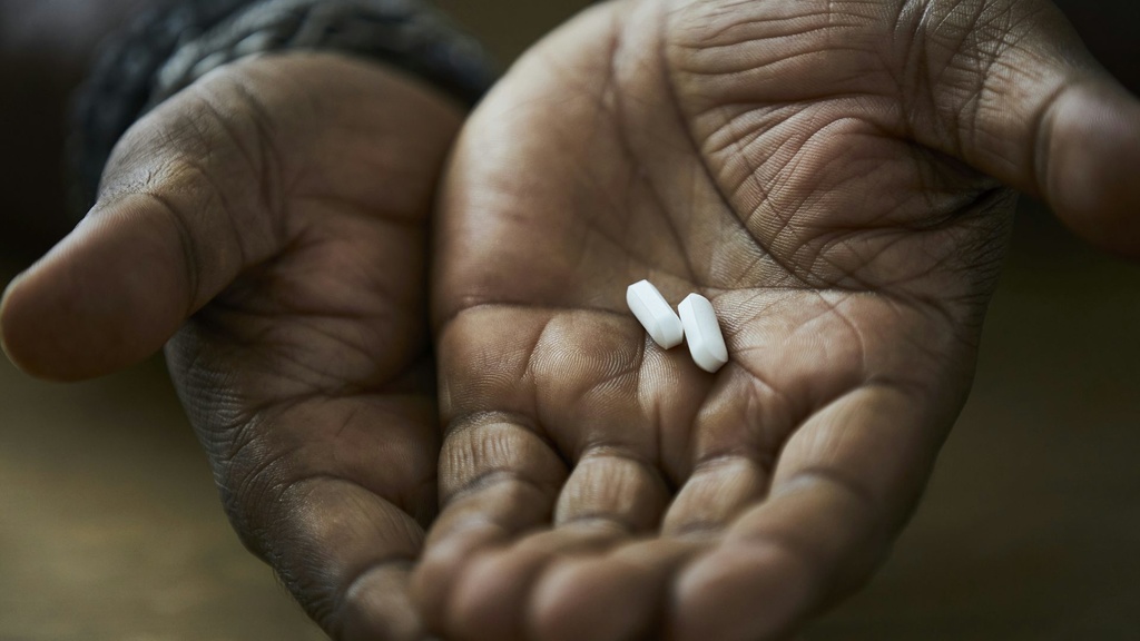 White pills cupped in the palms of a black man