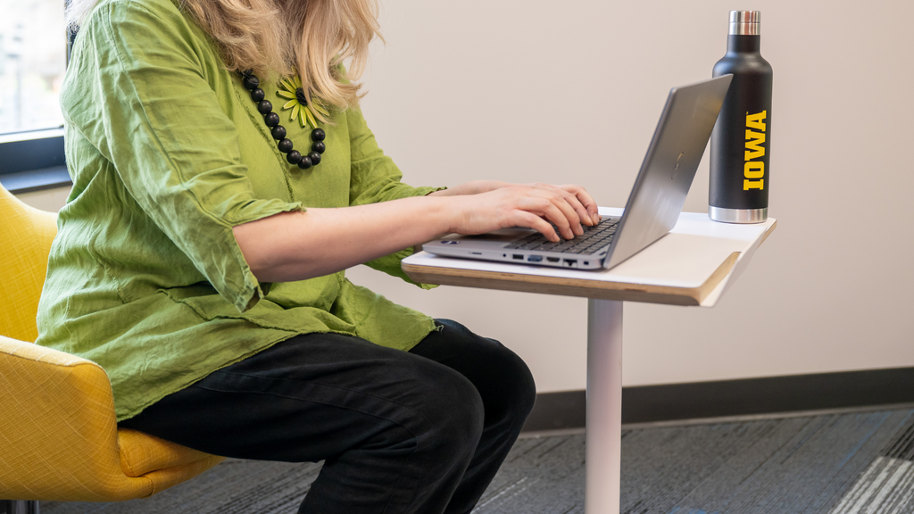 woman wearing green works on a laptop