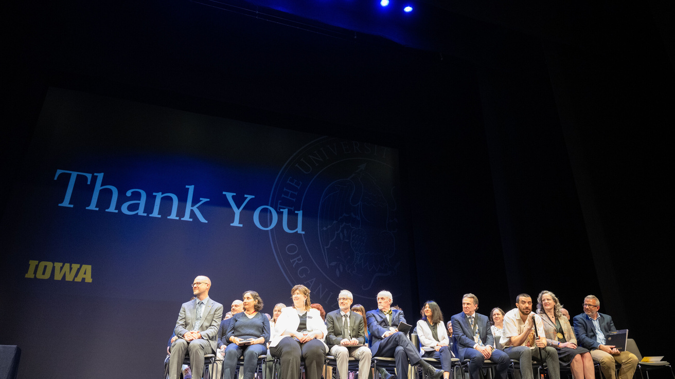 Recipients of 2025 Faculty and Staff awards on stage at Hancher Auditorium. 